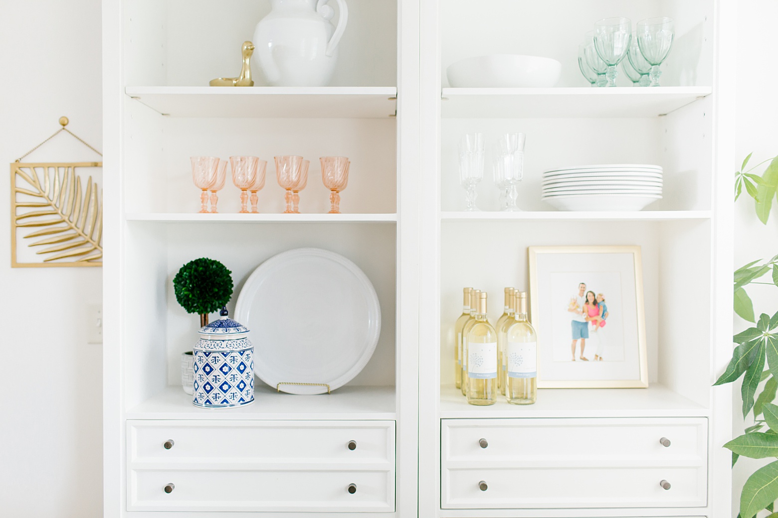A bright and colorful dining room tour on Megan Martin Creative featuring White dining shelves, bar cart, pink and navy home decor, vintage goblets, and Pottery Barn white dishes.