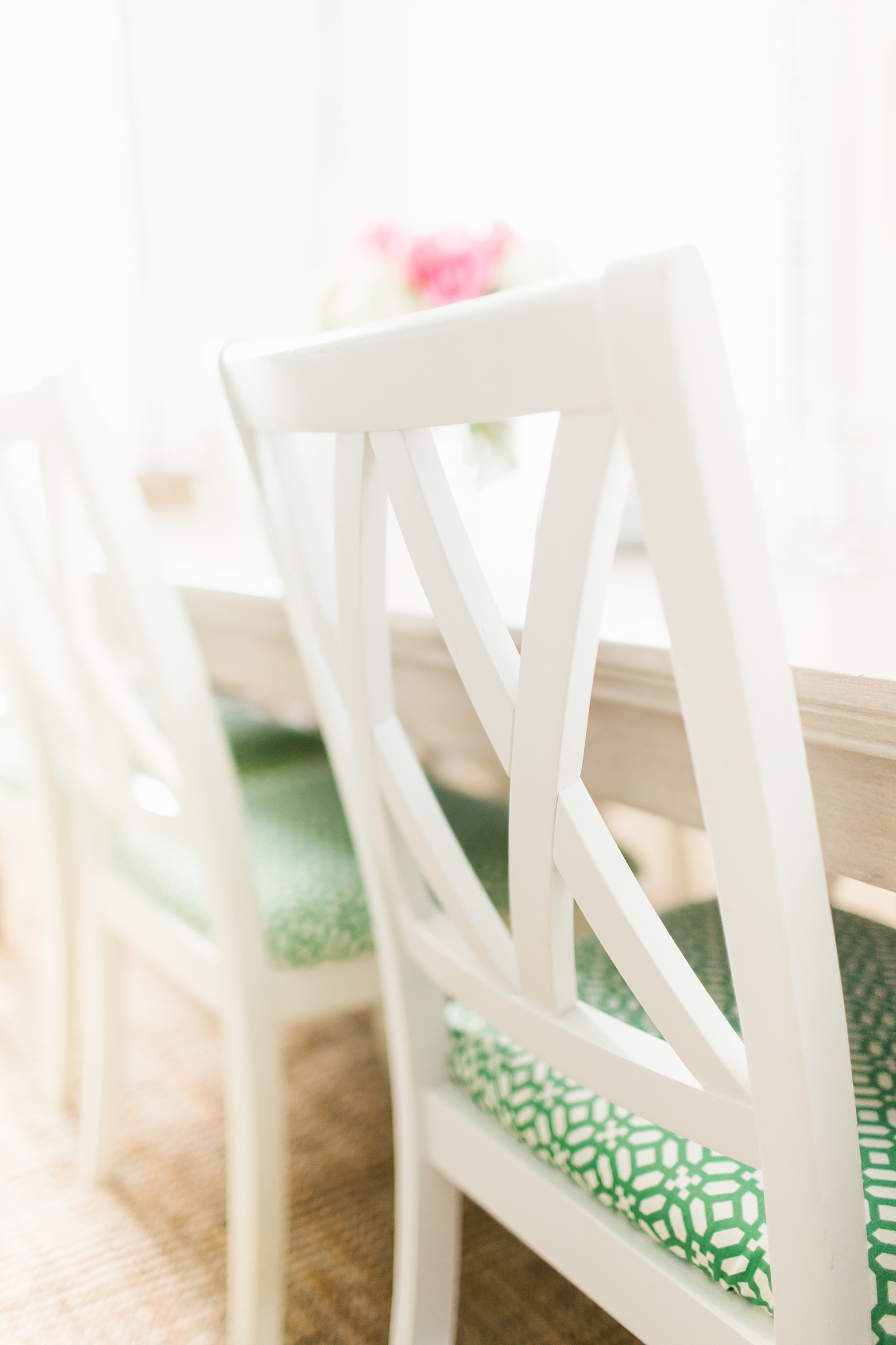 A bright and colorful dining room by Megan Martin Creative with white dining chairs and preppy green and white cushions