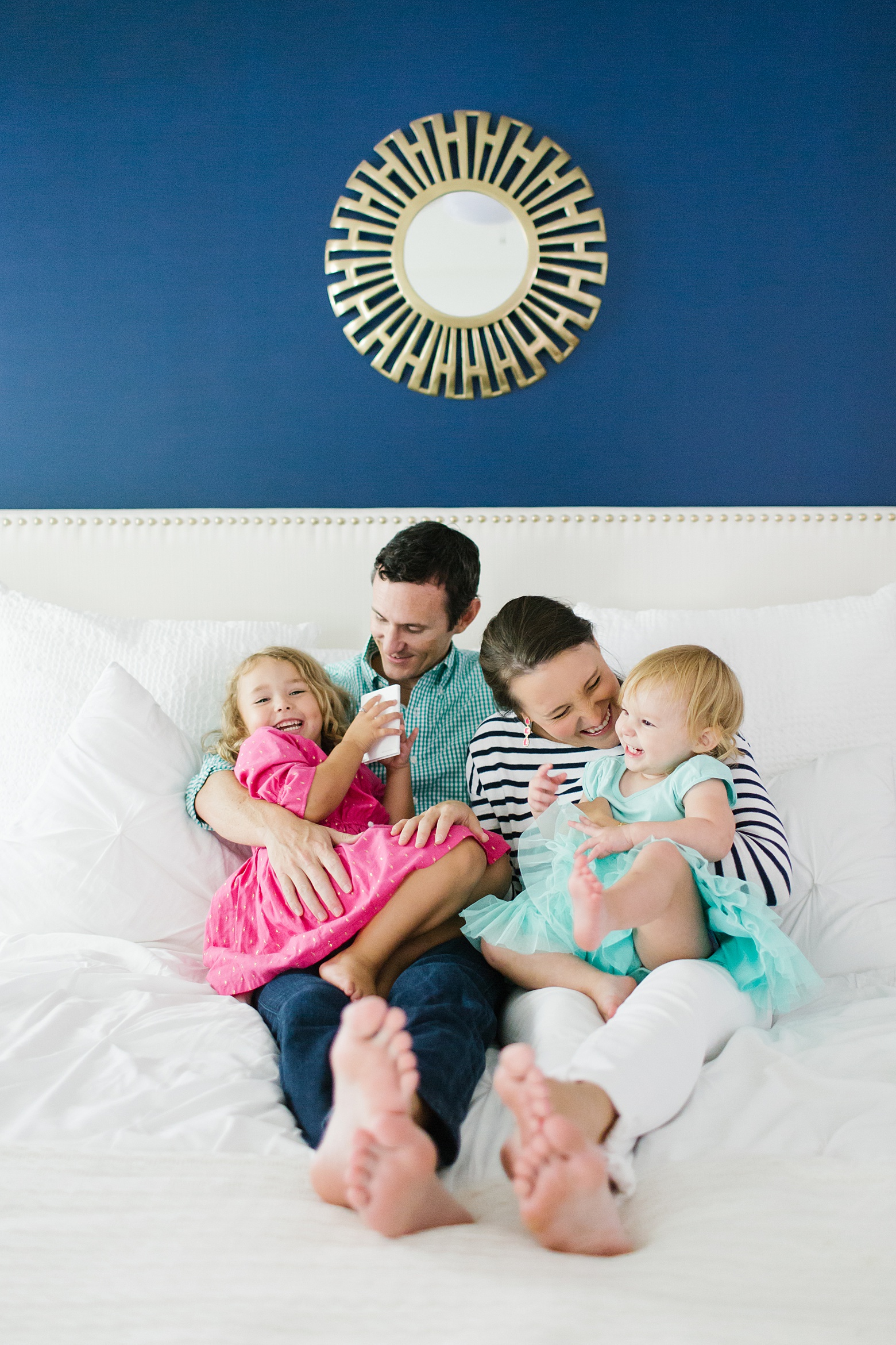 family friendly home, modern navy and pink master bedroom, gold mirror, white bed, nail head headboard